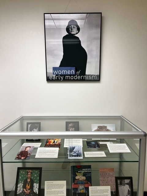 photo of woman in cape and hat above glass display case